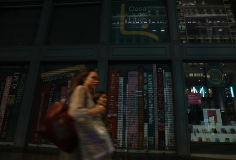 Unas mujeres caminan frente a un escaparate con la luz apagada en Madrid. E.P./Isabel Infantes