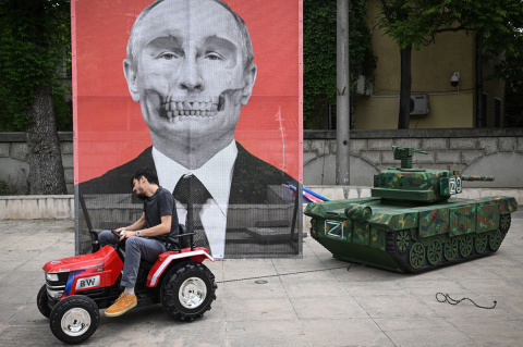  Un miembro de la ONG romaní "ARESEL" tira con un tractor de una maqueta de un tanque ruso frente a un retrato del presidente ruso Vladimir Putin, durante una protesta frente a la embajada rusa en Bucarest, el 16 de mayo de 2022.- AFP