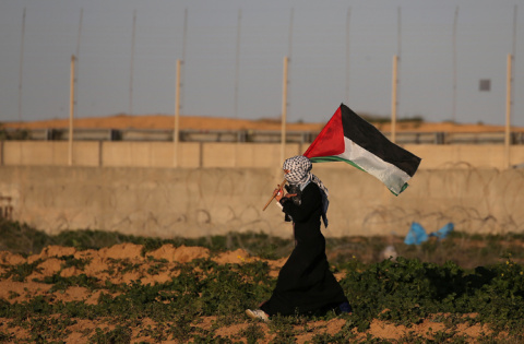 Una mujer con la bandera palestina en una protesta contra Israel en la frontera con Gaza. REUTERS/Ibraheem Abu Mustafa