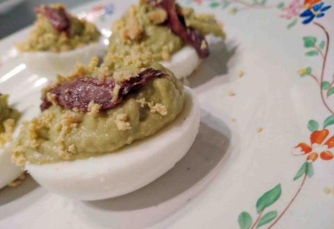 Huevo rellenos con aguacate, yema de huevo y trozos de anchoa.