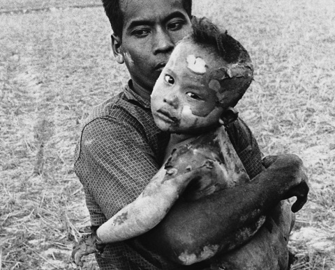 Un niño vietnamita con el cuerpo completamente quemado por el fecto de un bombardeo de napalm, en brazos de su padre, en una foto de marzo de 1964.