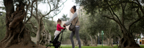 Una mujer pasea a una niña por un parque.- EFE