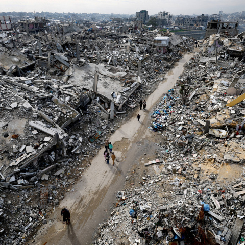 Palestinos caminan entre los escombros de edificios residenciales destruidos durante la guerra, en la víspera de Año Nuevo.