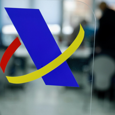 Logotipo de la Agencia Tributaria en una mampara en una oficina de dicha agencia, en Guzmán El Bueno.