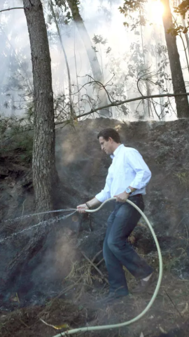 Feijóo, en 2006, simulando que apaga un fuego con una manguera doméstica en un monte de Ourense.