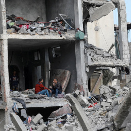 Dos palestinos conversan sentados dentro de un edificio destruido por los bombardeos israelíes, en Nuseirat, en el centro de la Franja de Gaza.