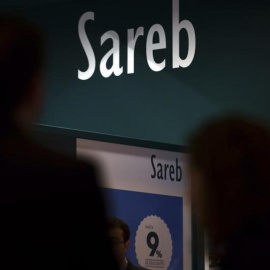 Varias personas pasan frente al puesto comercial de la Sareb, en una feria inmobiliaria.