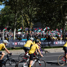 Personas con banderas de Palestina al lado de ciclistas que pasan por las inmediaciones de Atocha.