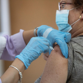Foto de archivo de una enfermera vacunando a una mujer contra la gripe y el Covid.