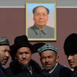 Chinos musulmanes de la etnia uigur, frente al retrato de Mao Zedong, en la Plaza Tiananmen de Pekín, en una foto de marzo de 2013. AFP/Mark RALSTON