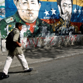 Un hombre camina junto a unos graffitis del héroe revolucionario sudamericano Simón Bolívar, el fallecido presidente de Venezuela, Hugo Chávez y el presidente de Venezuela, Nicolás Maduro, en el barrio José Félix Ribas en Caracas. REUTERS / Carlos 