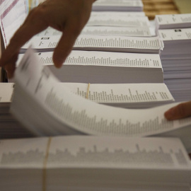 Un funcionario coloca los mazos de papeletas en un colegio electoral en Madrid. REUTERS