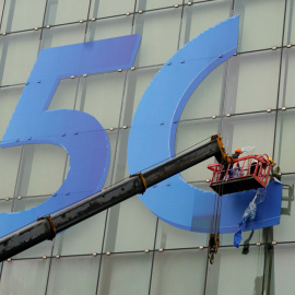 Dos operarios colocan un logo del 5G en el distrito financiero de Pudong, en Shanghai. REUTERS/Aly Song