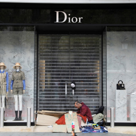 Un sin techo, en la puerta de una tienda de lujo en el Paseo de Gracia de Barcelona, durante la crisis del coronavirus. REUTERS/Nacho Doce