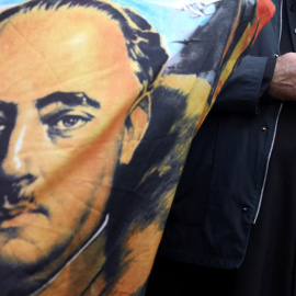 Un sacerdote sostiene un rosario junto a una bandera con el retrato del dictador Francisco Franco, en las afueras del cementerio Mingorrubio-El Pardo, el 24 de octubre. REUTERS / Sergio Perez