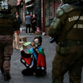 Una manifestante muestra a los policías un cartel que dice: "En Chile se tortura", durante una protesta contra el gobierno en Valparaíso. REUTERS/Rodrigo Garrido