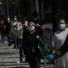 Varias personas con mascarillas guardan cola, manteniendo la distancia social, para entrar en un supermercado en Madrid. REUTERS/Susana Vera