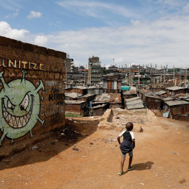 Un niño camina frente a un graffiti que promueve la lucha contra el coronavirus en los barrios bajos de Mathare, en Nairobi (Kenia). REUTERS / Baz Ratner