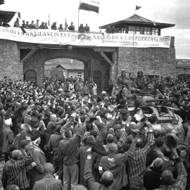  Prisioneros de Mauthausen saludan a la 11ª División Acorazada de los EE. UU. por su liberación bajo una pancarta escrita en español en unas sábanas.