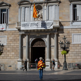 Un hombre envuelto en una estelada frente a la entrada del Palau de la Generalitat, en Barcelona. E.P./David Zorrakino