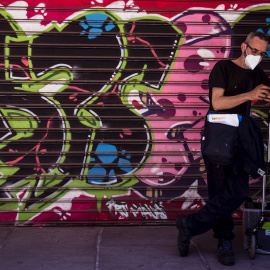  Un trabajador protegido con mascarilla consulta el móvil frente a un comercio cerrado en el popular barrio del Soho de Málaga. EFE/Jorge Zapata