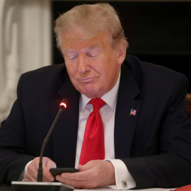  El presidente de EEUU, Donald Trump, mira su teléfono móvil durante una reunión en la Casa Blanca para analizar las medidas para la vuelta a la actividad de las pymes tras la pandemia. REUTERS/Leah Millis