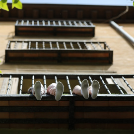Los pies de unos niños se asoman por el balcón de su casa en Madrid. E.P./Marta Fernández