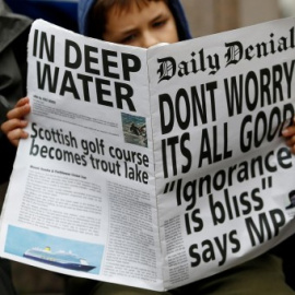 Un manifestante lee un periódico falso con el titular: "No se preocupe, todo va bien. Ignorancia es felicidad". REUTERS/Henry Nicholls