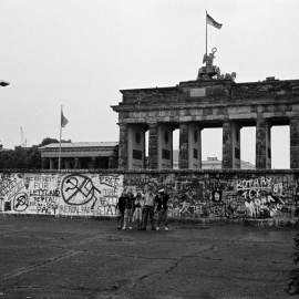 Foto de archivo de un grupo de turistas posa junto al Muro de Berlín, cerca de la Puerta de Brandenburgo, en junio de 1989. REUTERS/Fabrizio Bensch