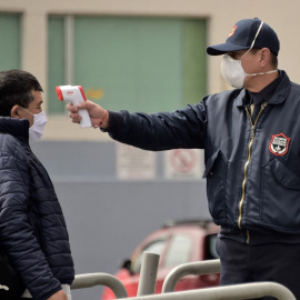 Un guardia de seguridad toma la temperatura a un pasajero de bus en Quito (Ecuador).- Rodrigo BUENDIA / AFP