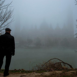  Un paseante contempla la silueta de la Basílica del Pilar cubierta por la niebla, en Zaragoza. EFE/Javier Cebollada