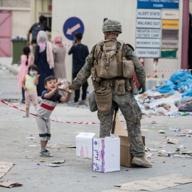 Un marine del Ejército estadounidense entrega un paquete de comida a un niño en el aeropuerto de Kabul. REUTERS