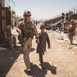 Un marine estadounidense acompaña a un menor junto a su familia para su evacuación, en el aeropuerto de Kabul (Afganistán). REUTERS