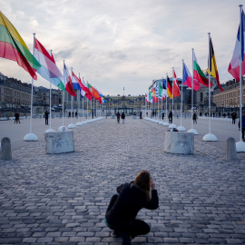 Una mujer toma una foto de las banderas de los países miembros de la UE, en frente del Palacio de Versalles, cerca de París, antes de la cumbre europea del pasado mes de marzo. E.P./DPA/Kay Nietfeld