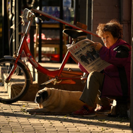 Una mujer lee el periódico en una calle de Pekín. AFP/Noel Celis