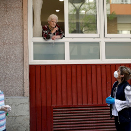 Una anciana, usuaria de una residencia geriática de L'Hospitalet de Llobregat (Barcelona), habla desde una ventana con una hija y un amigo de la familia. EFE/Toni Albir