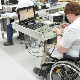 Discapacitado trabajando en una fábrica de ensamblaje de componentes electrónicos.