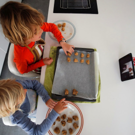 Unos niños preparan unas galletas siguiendo la receta que les dan sus abuelos a través de una 'tablet'. REUTERS/Albert Gea