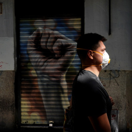 Un hombre con mascarilla pasa por delante de un comercio cerrado en Madrid. REUTERS/Juan Medina