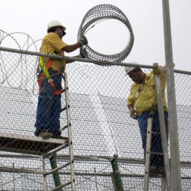 Dos operarios reparando la concertina de la valla que separa España y Marruecos, en Melilla. EFE