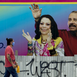 Un hombre con mascarilla pasa delante de un cartel con la imagen del presidente de Nicaragua Daniel Ortega y su esposa Rosario Murillo, en Managua. EFE/Jorge Torres