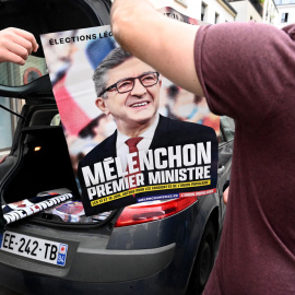  Militantes del movimiento izquierdista francés La France Insoumise (LFI) exhiben un cartel de campaña que dice en francés "Melenchon, primer ministro" fuera de la sede de LFI en París el 3 de mayo de 2022.- EMMANUEL DUNAND / AFP