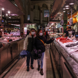 Dos personas pasan por un puesto de pescado en el Mercado Central de Valencia, a 24 de marzo de 2022, en Valencia. Rober Solsona / Europa Press