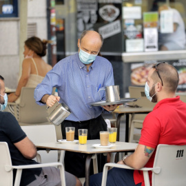 Un camarero sirve a dos clientes en una terraza de un bar en Madrid. REUTERS/Javier Barbancho