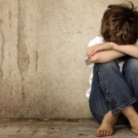 Imagen de archivo de un niño sentado en el suelo tapando su rostro.- EFE