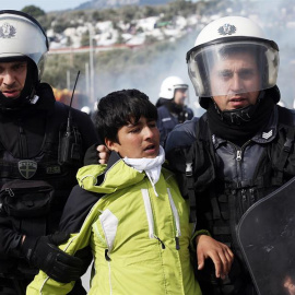  Dos policías antidisturbios detienen a un niño que llora mientras decenas de solicitantes de asilo llegados de Siria se manifiestan a las afueras del campo de refugiados de Moria, en la isla griega de Lesbos. EFE/Orestis Panagiotou