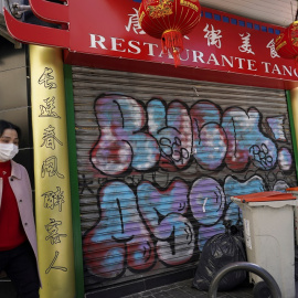Una mujer con mascarilla pasa junto a un restaurante chino cerrado, en el barrio madrileño de Usera. REUTERS/Juan Medina
