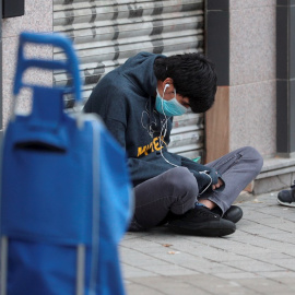 Una persona espera sentada en el suelo en una fila para recoger alimentos. EFE/Rodrigo Jiménez