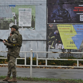  Un policía ucraniano habla por teléfono junto a un cartel (derecha, arriba) que pide a los residentes que denuncien a quienes colaboraron con las fuerzas rusas, en Kherson el 8 de diciembre de 2022, en medio de la invasión rusa de Ucrania.Genya SAVILO