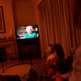 Una mujer atiende el mensaje televisado de la reina Isabel II, en su vivienda en la localidad británica de Weybridge. REUTERS/Peter Nicholls